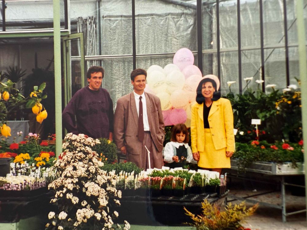 Die Inhaber der Gärtnerei Mebo Flor in Bozen stehen im Gewächshaus zwischen farbenfrohen Blumen und Pflanzen.